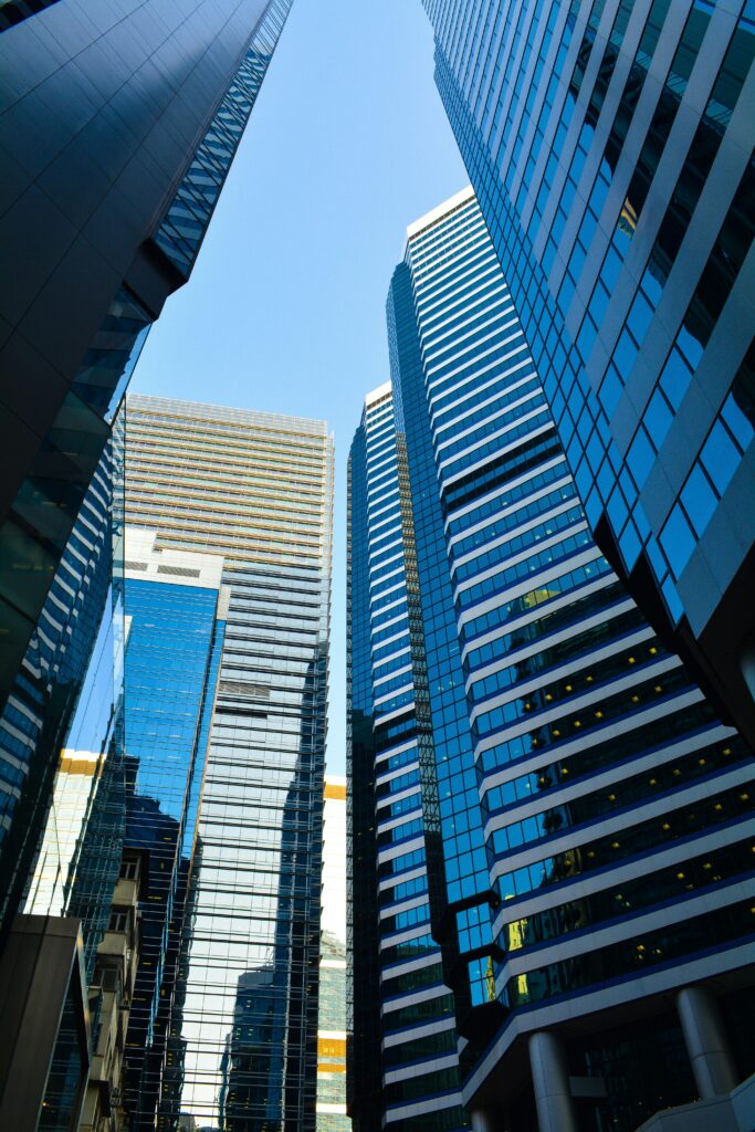 Vertical shot of modern skyscrapers in downtown Hong Kong with reflective glass facades.
